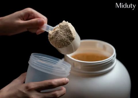 En skopa fylld med proteinpulver lyfts ur en vit behållare.