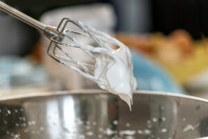 Ballongvisp med blank, fast marängsmet över en rostfri bunke