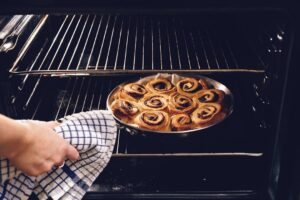 Nybakade kanelbullar i en rund form tas ut ur ugnen